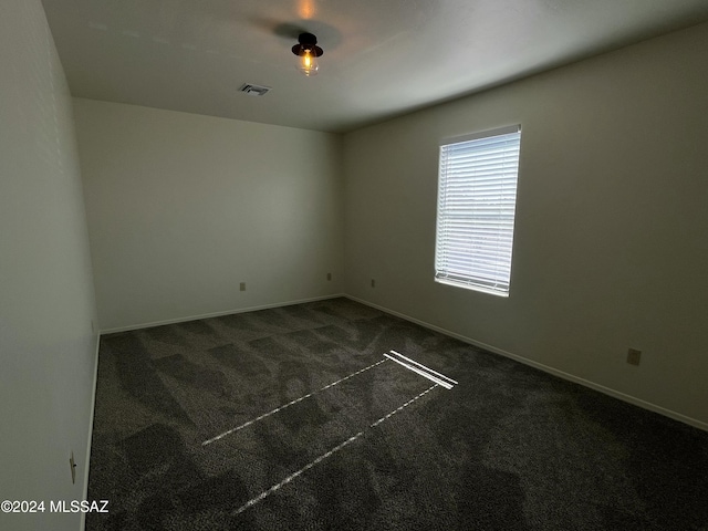 spare room with dark colored carpet