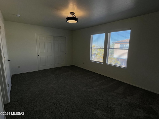 unfurnished bedroom with a closet and dark colored carpet