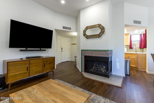 living room featuring a tile fireplace, dark hardwood / wood-style floors, and sink