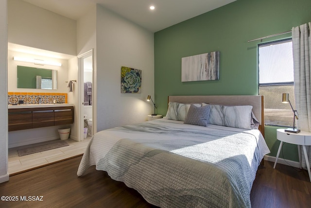 bedroom with ensuite bathroom and dark wood-type flooring