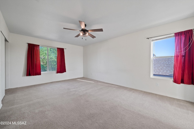 carpeted spare room with ceiling fan