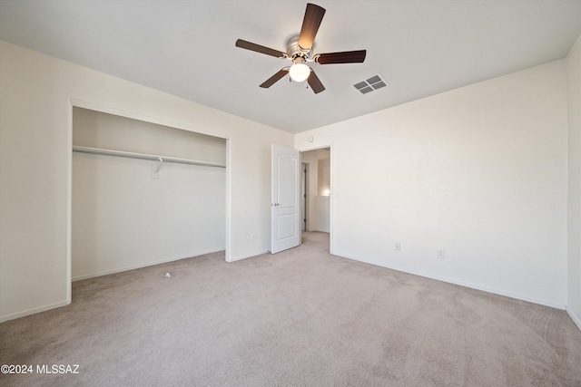 unfurnished bedroom with a closet, light colored carpet, and ceiling fan