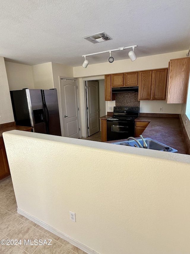 kitchen featuring black electric range oven, rail lighting, sink, light tile patterned floors, and stainless steel fridge with ice dispenser