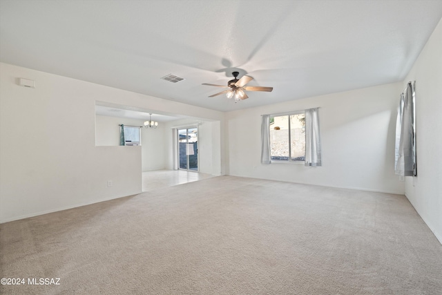 spare room featuring light carpet and ceiling fan with notable chandelier