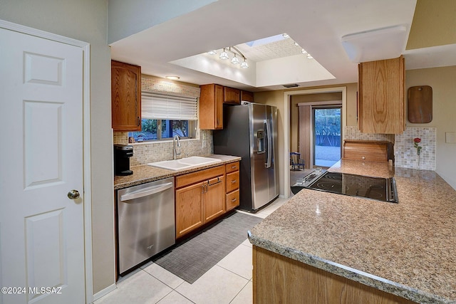 kitchen with sink, stainless steel appliances, a raised ceiling, decorative backsplash, and light tile patterned floors