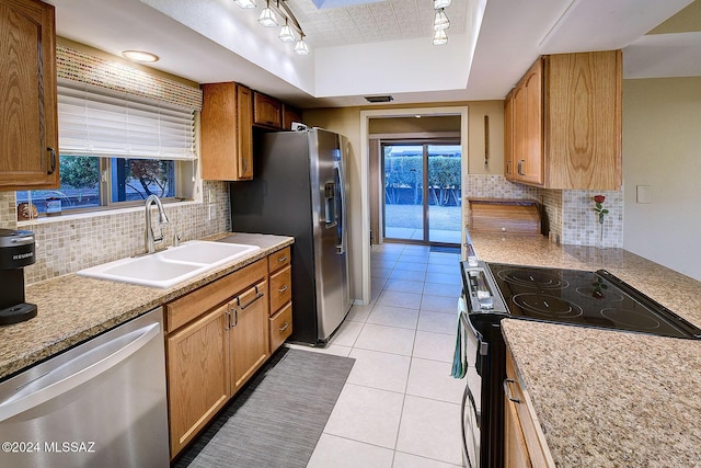 kitchen featuring sink, backsplash, track lighting, light tile patterned floors, and appliances with stainless steel finishes