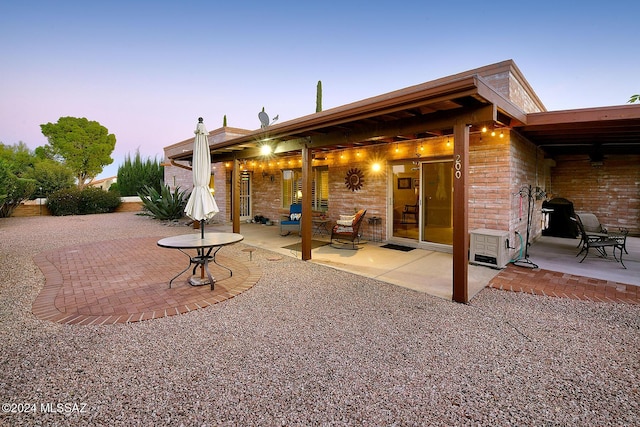 back house at dusk featuring a patio