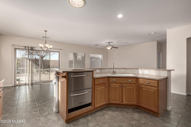 kitchen featuring hanging light fixtures, sink, ceiling fan with notable chandelier, and dark tile patterned flooring