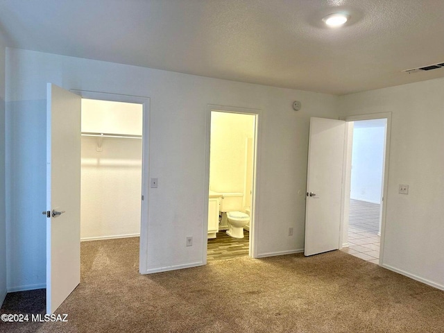 unfurnished bedroom with connected bathroom, carpet floors, a spacious closet, and a closet