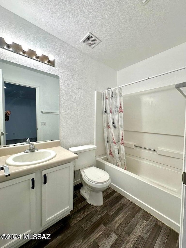 full bathroom with hardwood / wood-style floors, shower / bath combination with curtain, a textured ceiling, toilet, and vanity