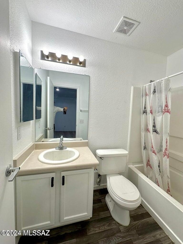 full bathroom featuring shower / bath combination with curtain, vanity, a textured ceiling, hardwood / wood-style flooring, and toilet