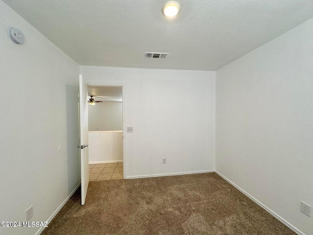 carpeted empty room with ceiling fan and a textured ceiling