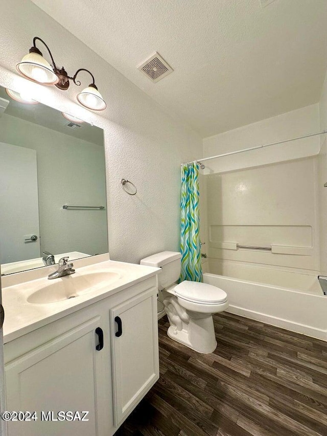 full bathroom with hardwood / wood-style floors, vanity, shower / bath combo, toilet, and a textured ceiling