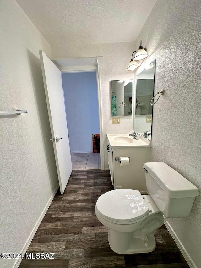 bathroom featuring hardwood / wood-style flooring, vanity, toilet, and a textured ceiling