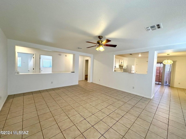 unfurnished living room featuring ceiling fan, light tile patterned flooring, and a textured ceiling