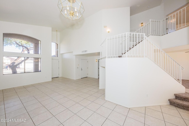 entryway with a towering ceiling, light tile patterned flooring, and an inviting chandelier