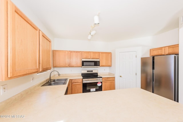 kitchen featuring appliances with stainless steel finishes, light brown cabinetry, and sink