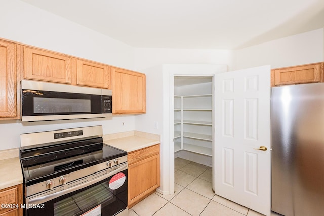 kitchen featuring light brown cabinets, light tile patterned floors, and stainless steel appliances