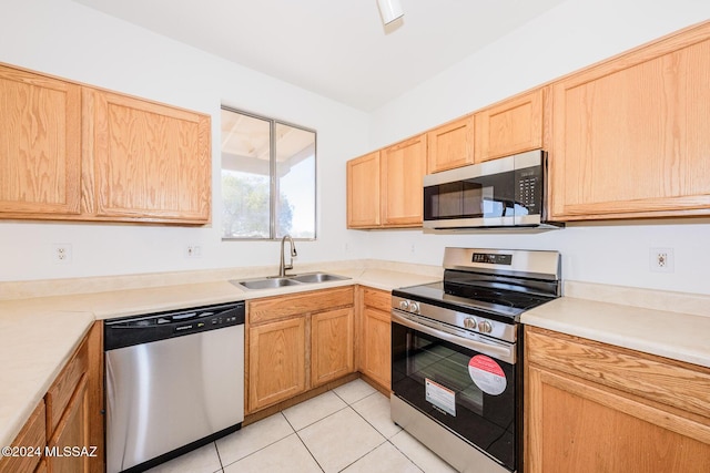 kitchen with light tile patterned floors, stainless steel appliances, light brown cabinetry, and sink