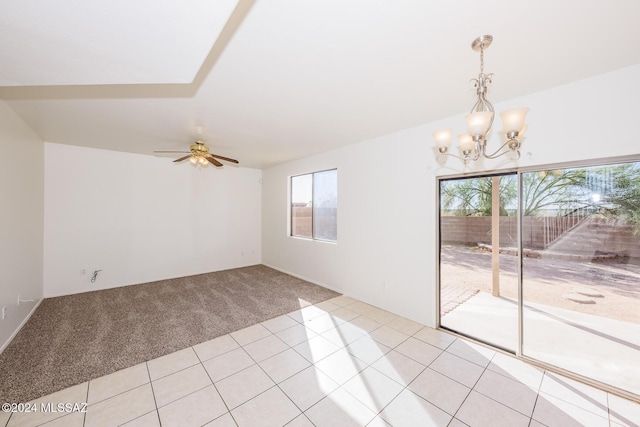 carpeted spare room with ceiling fan with notable chandelier