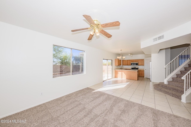 unfurnished living room with sink, light tile patterned floors, and ceiling fan with notable chandelier