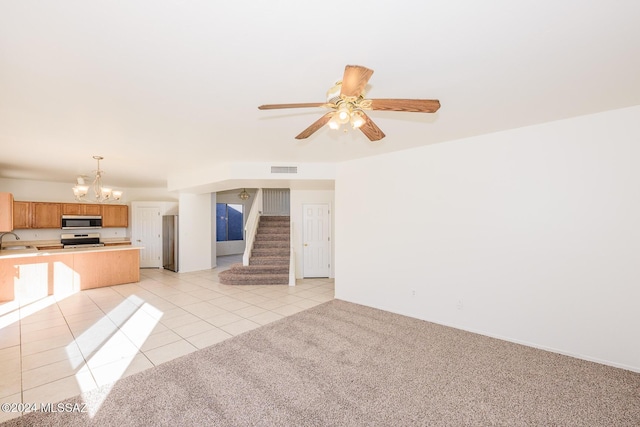 unfurnished living room with ceiling fan with notable chandelier, light tile patterned flooring, and sink