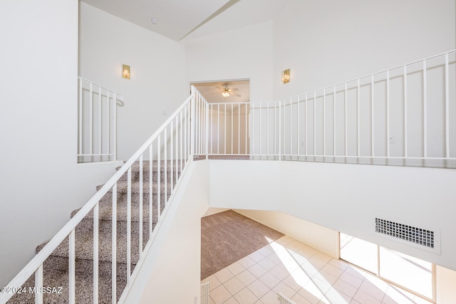 stairs with tile patterned floors and a towering ceiling