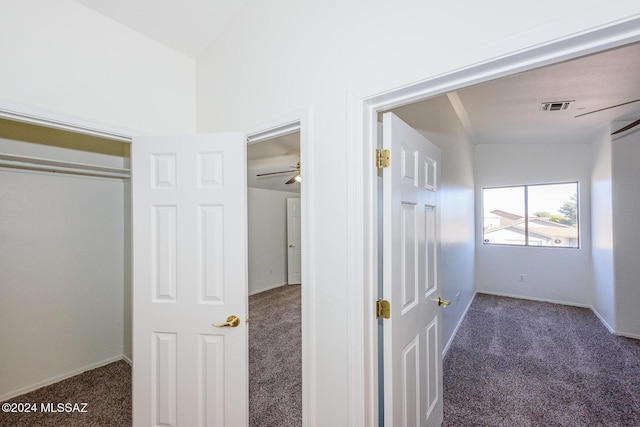 corridor with dark colored carpet and lofted ceiling