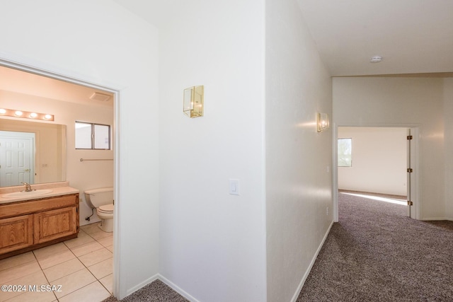 hallway featuring sink and light colored carpet