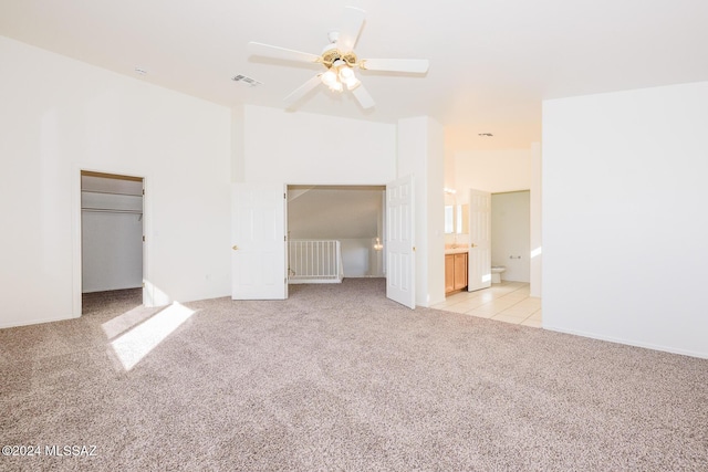 unfurnished bedroom with light carpet, a closet, ensuite bath, and ceiling fan