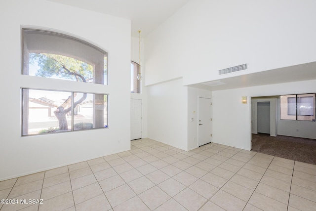 empty room with light tile patterned floors and high vaulted ceiling