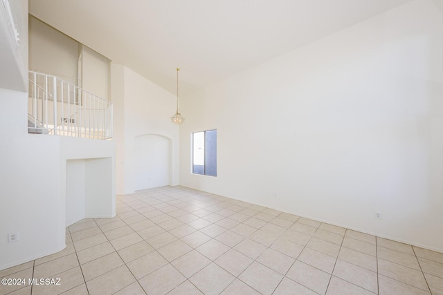 tiled spare room with a chandelier and a high ceiling