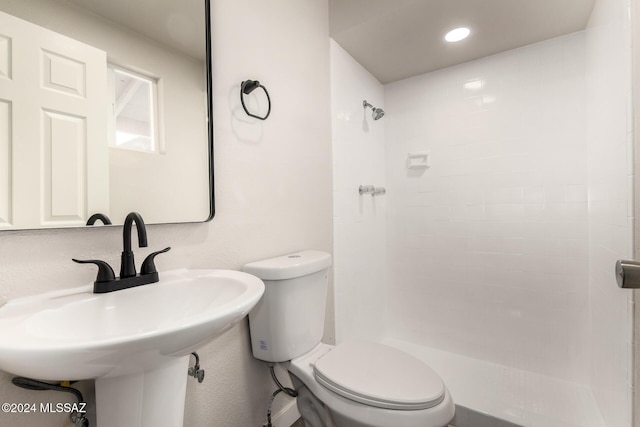 bathroom featuring walk in shower, sink, and toilet