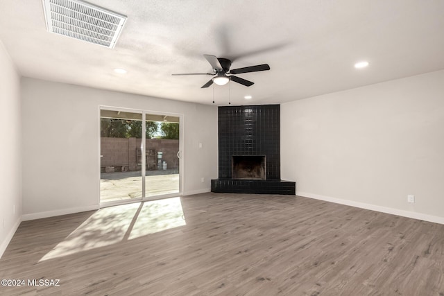 unfurnished living room featuring ceiling fan, a large fireplace, and wood-type flooring