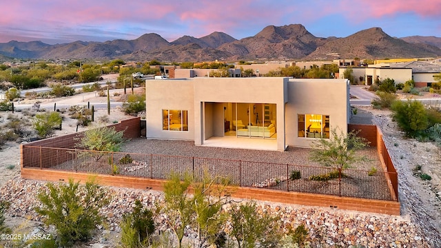 back house at dusk featuring a patio area and a mountain view