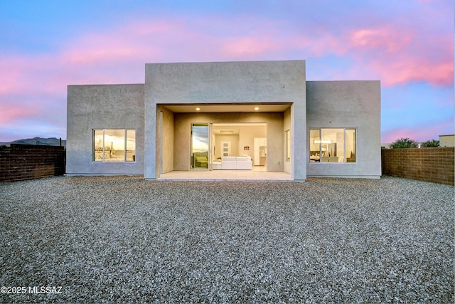 back house at dusk featuring a patio