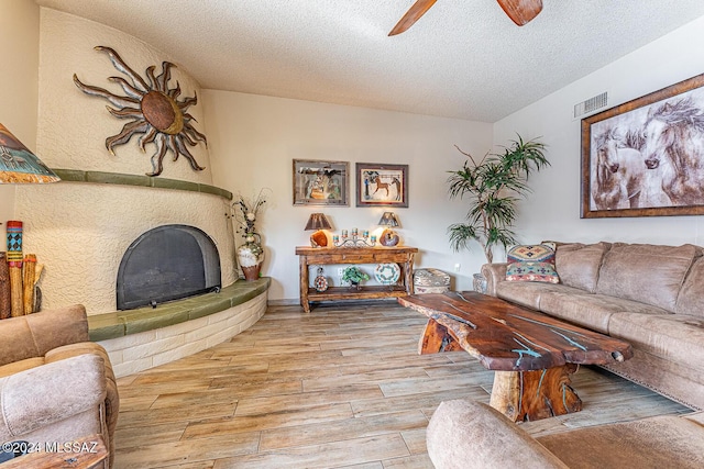 living room featuring ceiling fan, light hardwood / wood-style floors, and a textured ceiling