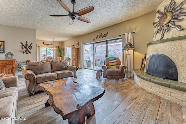 living room with ceiling fan, a large fireplace, and a textured ceiling