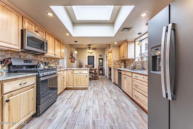 kitchen featuring a raised ceiling, sink, hanging light fixtures, appliances with stainless steel finishes, and kitchen peninsula