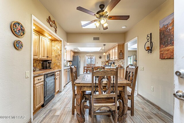 dining space featuring a skylight, ceiling fan, and beverage cooler