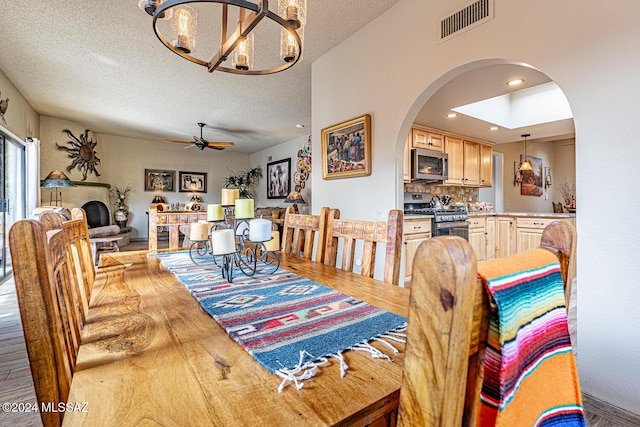 dining room featuring ceiling fan with notable chandelier, light hardwood / wood-style floors, and a textured ceiling