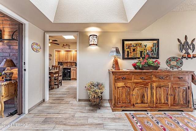 hallway featuring light hardwood / wood-style floors, a textured ceiling, and beverage cooler