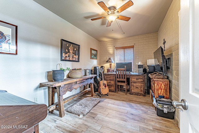 home office featuring ceiling fan, brick wall, and light wood-type flooring