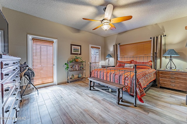 bedroom with a textured ceiling, light wood-type flooring, and ceiling fan