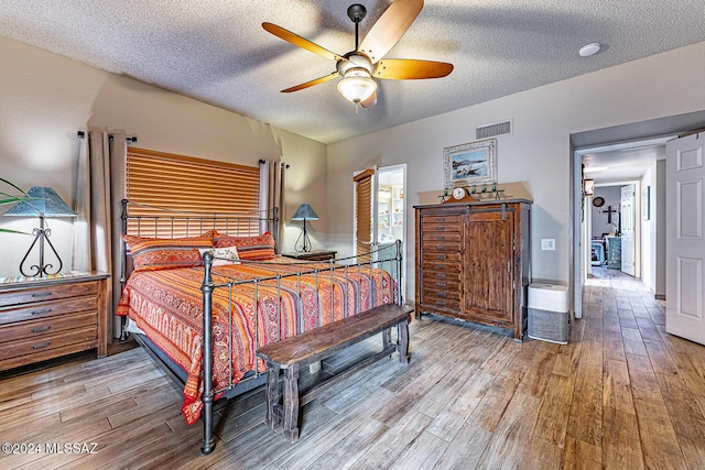 bedroom with a textured ceiling, hardwood / wood-style flooring, and ceiling fan