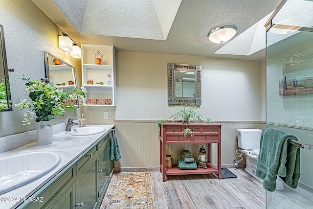 bathroom featuring hardwood / wood-style floors, vanity, a skylight, toilet, and a textured ceiling