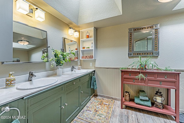 bathroom featuring wood walls, hardwood / wood-style floors, vanity, and a textured ceiling