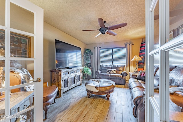 living room featuring ceiling fan, a textured ceiling, and hardwood / wood-style flooring