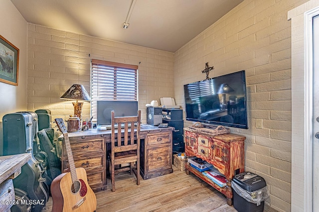 home office featuring light hardwood / wood-style flooring and brick wall