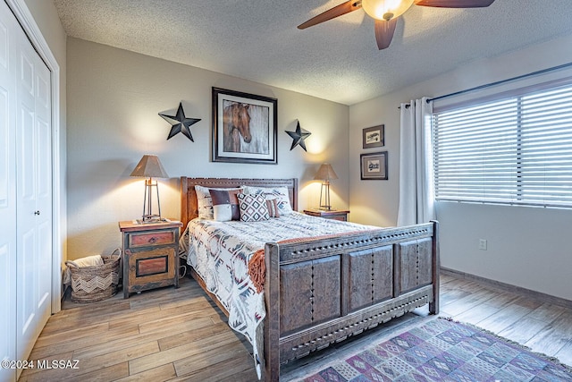 bedroom with ceiling fan, light wood-type flooring, a textured ceiling, and a closet